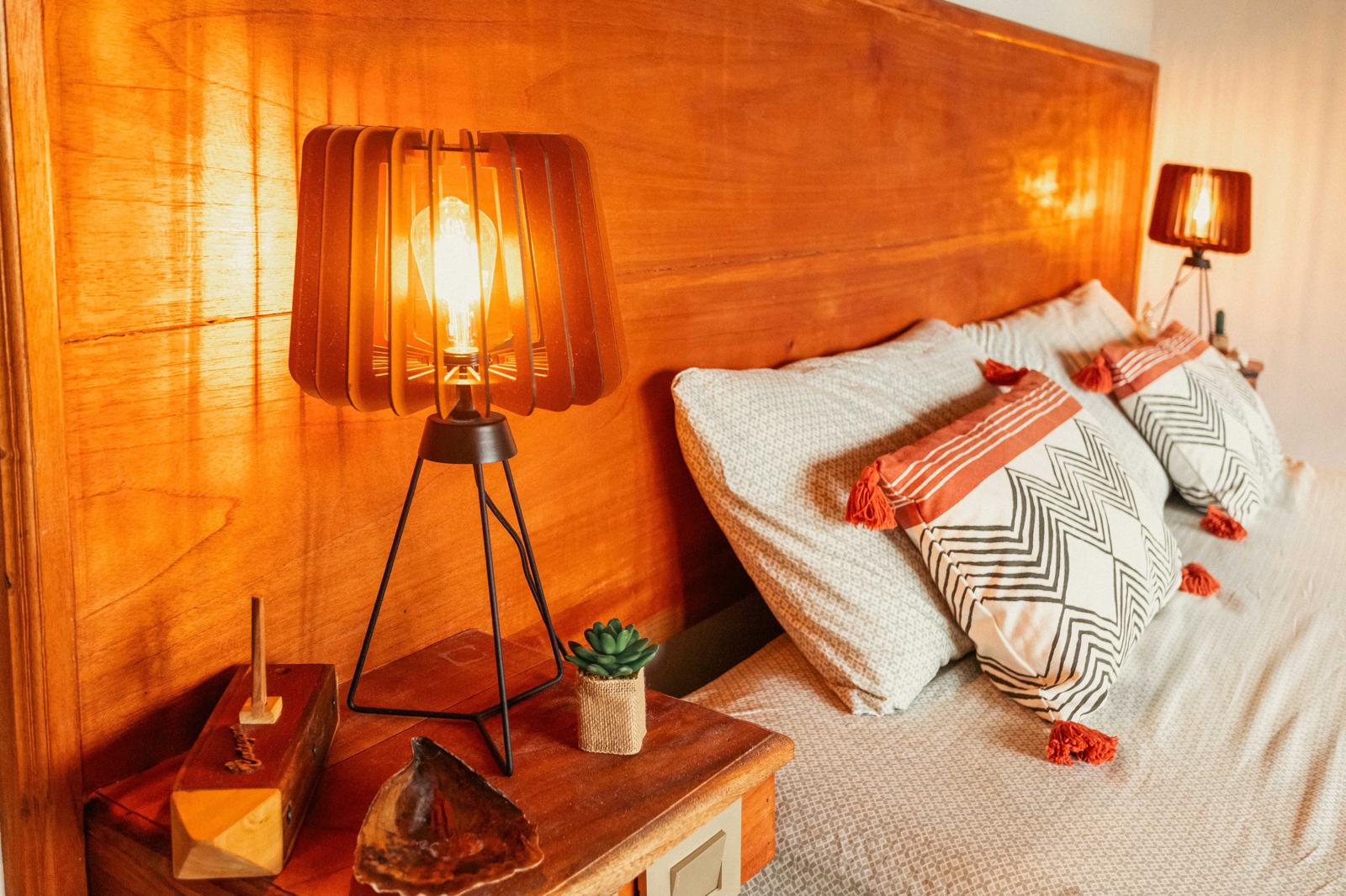 Hand-made timber lamp glowing against a teak headboard